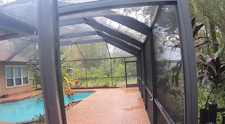 Screened pool enclosure with a clean brick paver deck after cleaning