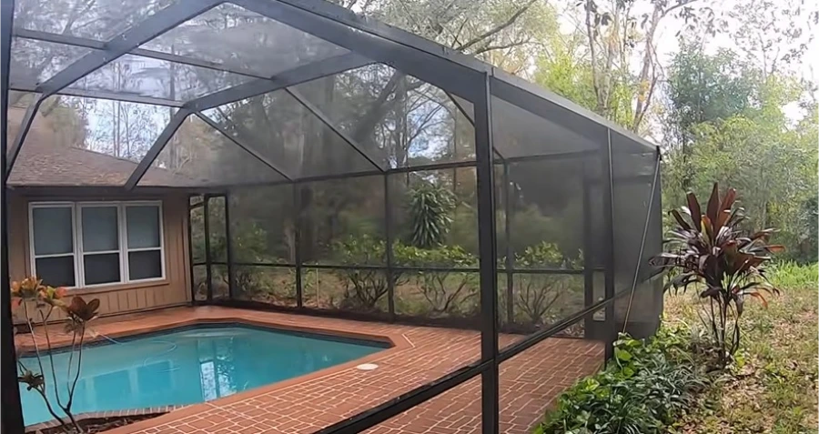 Pool enclosure with clean screens after cleaning, with the pool and brick deck behind