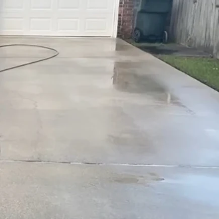 Same concrete driveway at a Boynton Beach home after pressure washing, with clean even concrete
