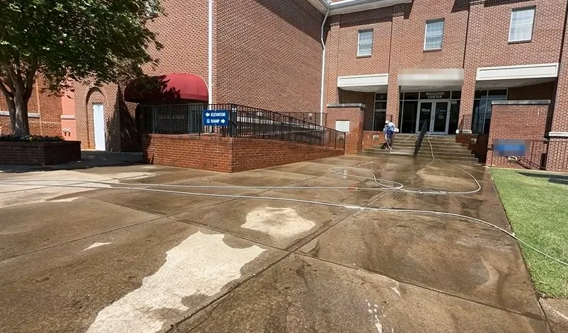 Stained concrete walkway at a commercial building entrance before pressure washing